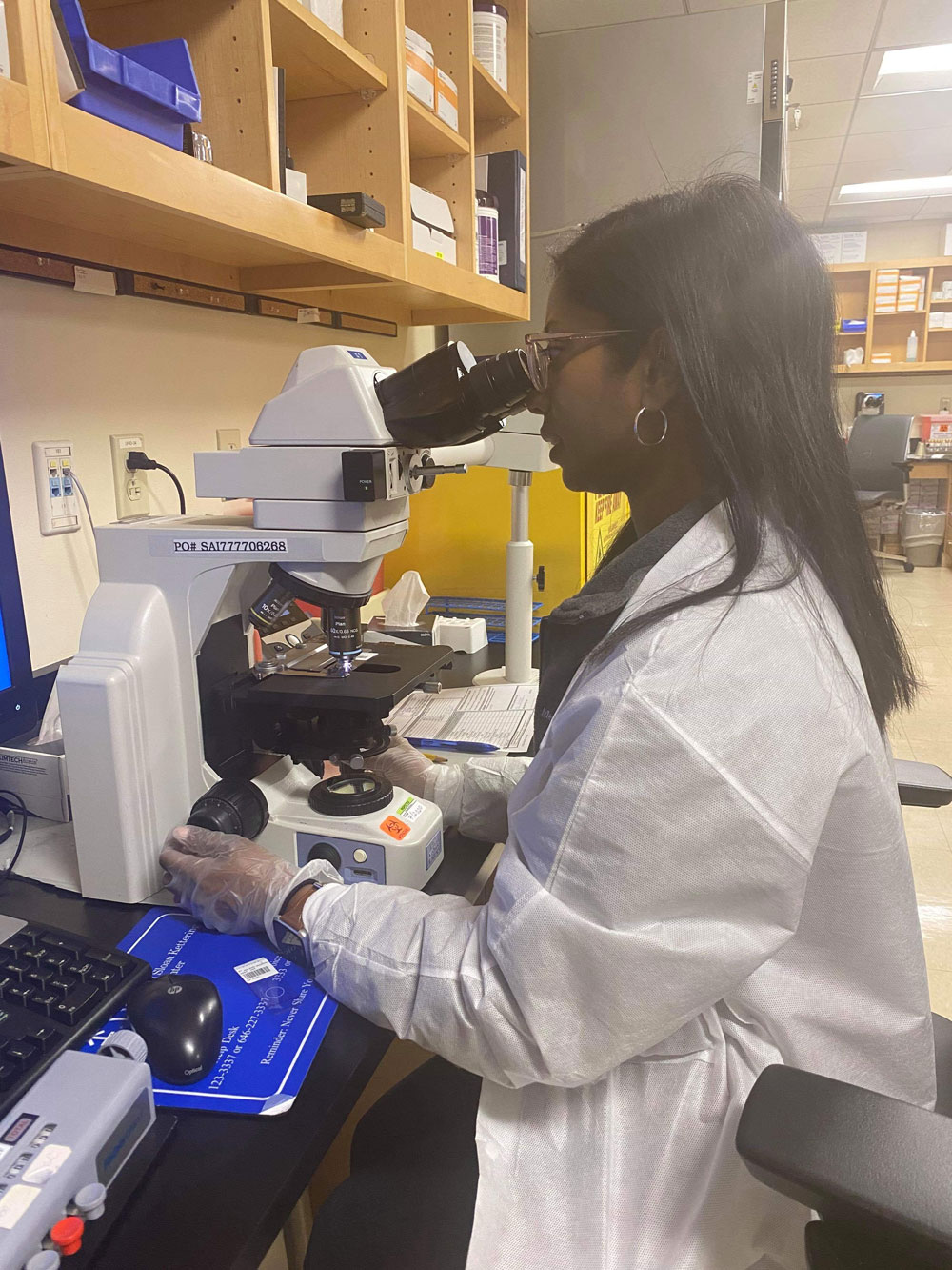 Image of MSK colleague in lab coat looking in microscope